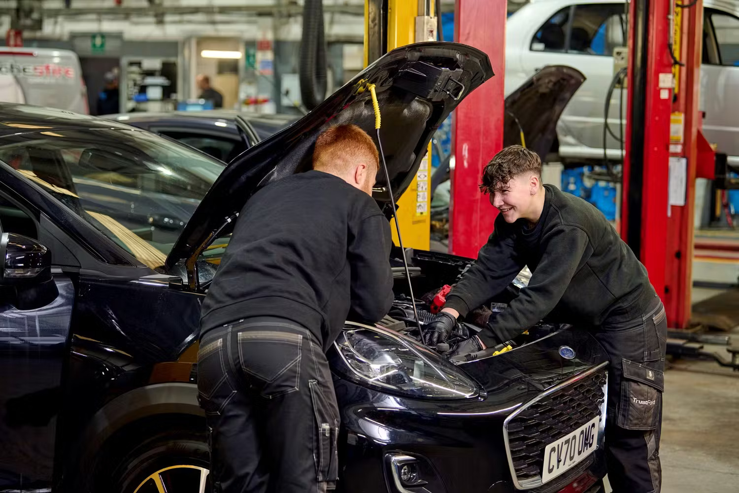 Two mechanics working on a car